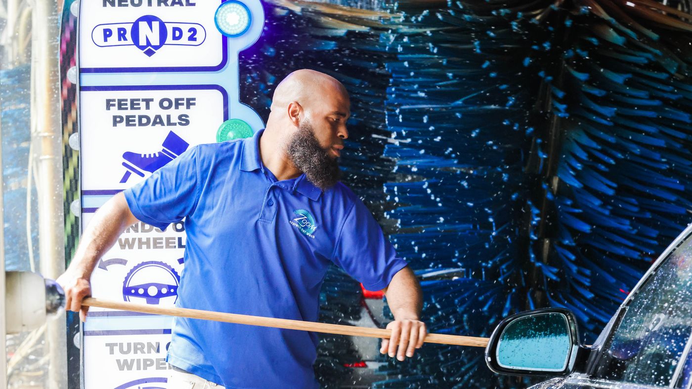 A Zoom Express attendant guiding a vehicle into the wash tunnel