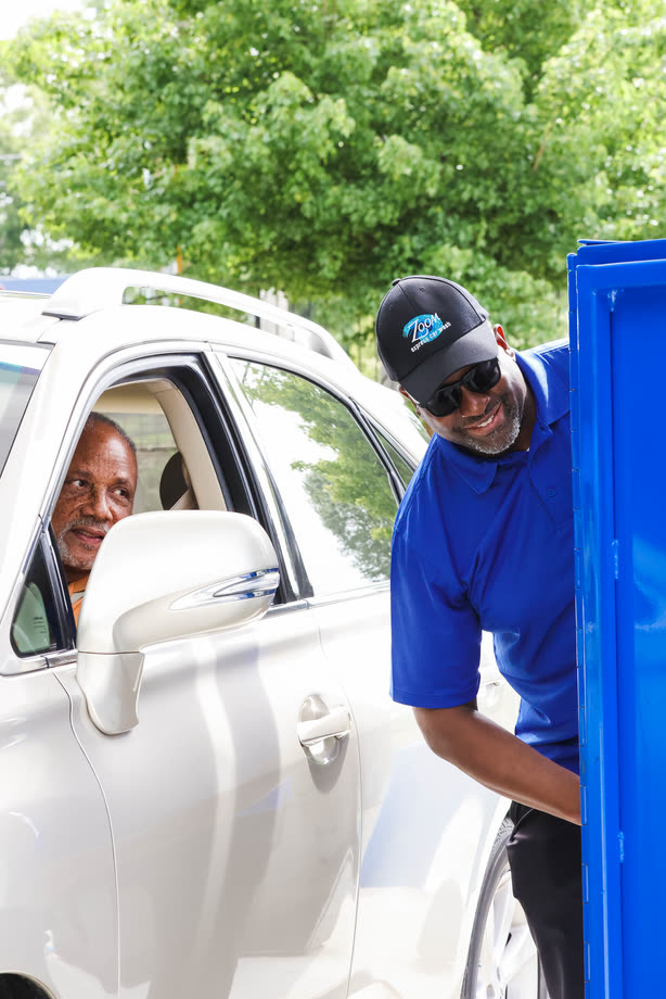 A Zoom Express team member leaning in to greet a driver at the pay station